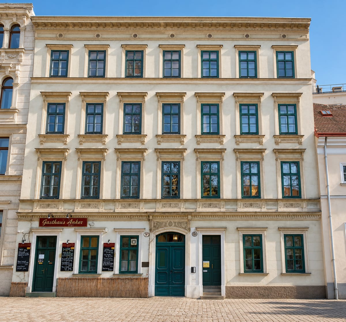 Gründerzeit-Mehrfamilienhaus mit heller Fassade, grünen Fenstern und Ladenlokal im Erdgeschoss